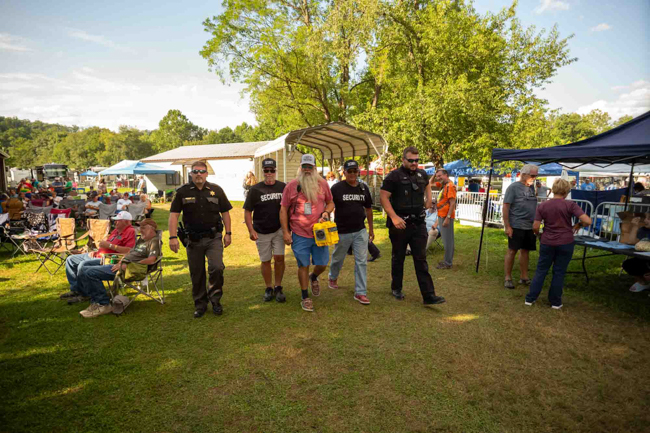 Festival promoter John Bowers flanked by security at Pickin' in Parsons 2025 - photo © Jeromie Stephens